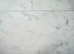 Biela mramorová dlažba s jemným sivým žilkovaním, detail povrchu.